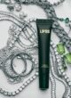 Блиск для губ LIPSS Smells like money: темно-зелена туба серед срібних прикрас із камінням