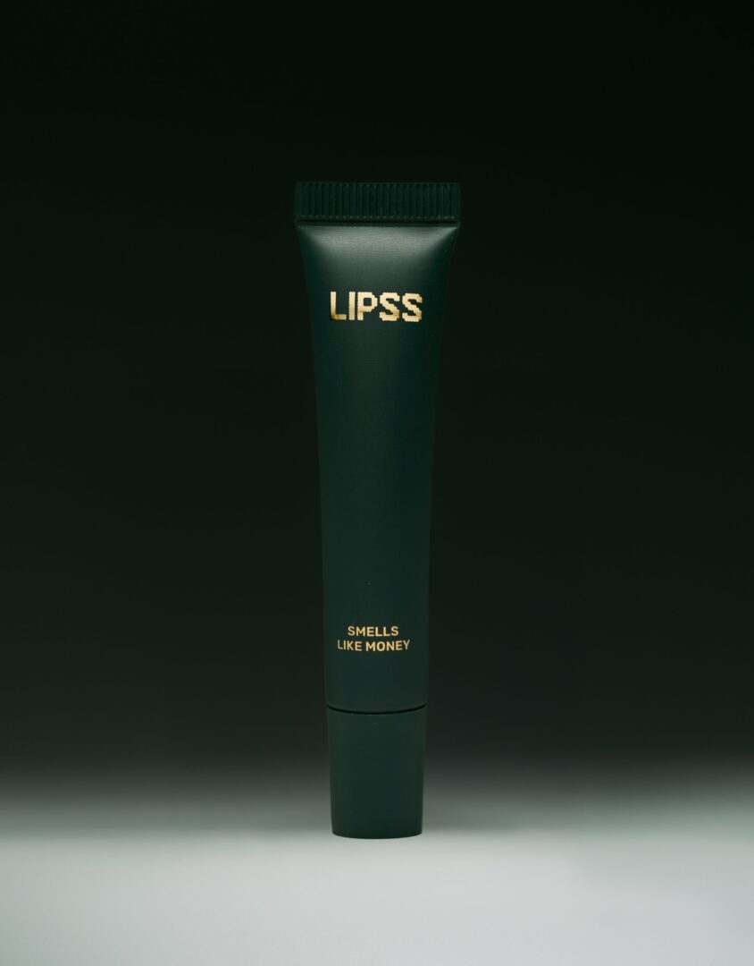 Блиск для губ LIPSS Smells like money 8 мл: темно-зелена туба з золотим логотипом на темному тлі