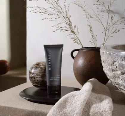 Крем для гоління Rituals Homme Shave Cream 70ml: чорна туба на таці поруч із глиняною вазою та рушником