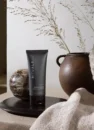Крем для гоління Rituals Homme Shave Cream 70ml: чорна туба на таці поруч із глиняною вазою та рушником