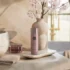 Олія для тіла Rituals Sakura Shower Oil 200 мл: рожевий флакон на кам'яній підставці біля гілок сакури