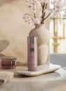 Олія для тіла Rituals Sakura Shower Oil 200 мл: рожевий флакон на кам'яній підставці біля гілок сакури
