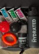 Бокс FITNESS BOX згори: батончики FIZI, червоний і чорний масажні м'ячики, помаранчевий еспандер 32 кг