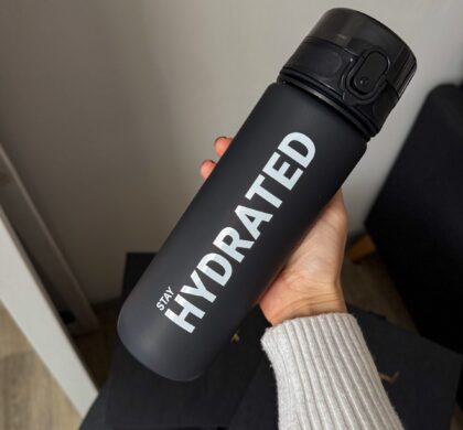 Спортивна пляшка для води 700 мл, чорна матова з написом STAY HYDRATED у руці