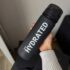 Спортивна пляшка для води 700 мл, чорна матова з написом STAY HYDRATED у руці
