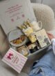 COOKIE & TEA на кріслі поруч із дівчиною в джинсах: відкрита коробка й рожева листівка з бантом