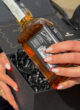 BOSS: руки з червоним манікюром дістають пляшку Jack Daniel's Old Time з чорної коробки