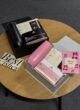 COFFEE MINI PINK поруч із COFFEE MINI BLACK на круглому столі: термочашки, кава та листівки