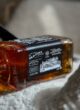 Бокс JACK: пляшка віскі Jack Daniel's лежить на світлому пледі в променях сонця