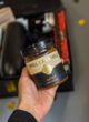 Бокс JUST BECAUSE: баночка солоної карамелі Spell Caramell у руці над відкритою коробкою