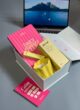 Бокс SUNNY GIRL: біла коробка з планером Daily Planner Club, жовтою свічкою та бальзамом LIPSS біля ноутбука