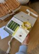 CALM & CARE: рука з перлинним браслетом тримає шоколад Lviv Handmade над відкритою коробкою