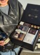 Бокс MAN’S LUXURY: жінка в шкіряній куртці тримає відкриту коробку та пляшку St-Remy