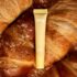 Блиск для губ LIPSS Butter Croissant 8 мл: жовта туба лежить на свіжих круасанах