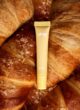 Блиск для губ LIPSS Butter Croissant 8 мл: жовта туба лежить на свіжих круасанах