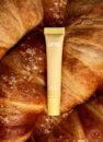 Блиск для губ LIPSS Butter Croissant 8 мл: жовта туба лежить на свіжих круасанах