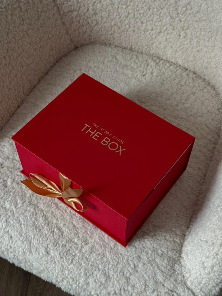 Червона коробка The Box на світлому кріслі