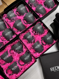 Чорні чашки REDKEN у рожевому наповнювачі у відкритих коробках