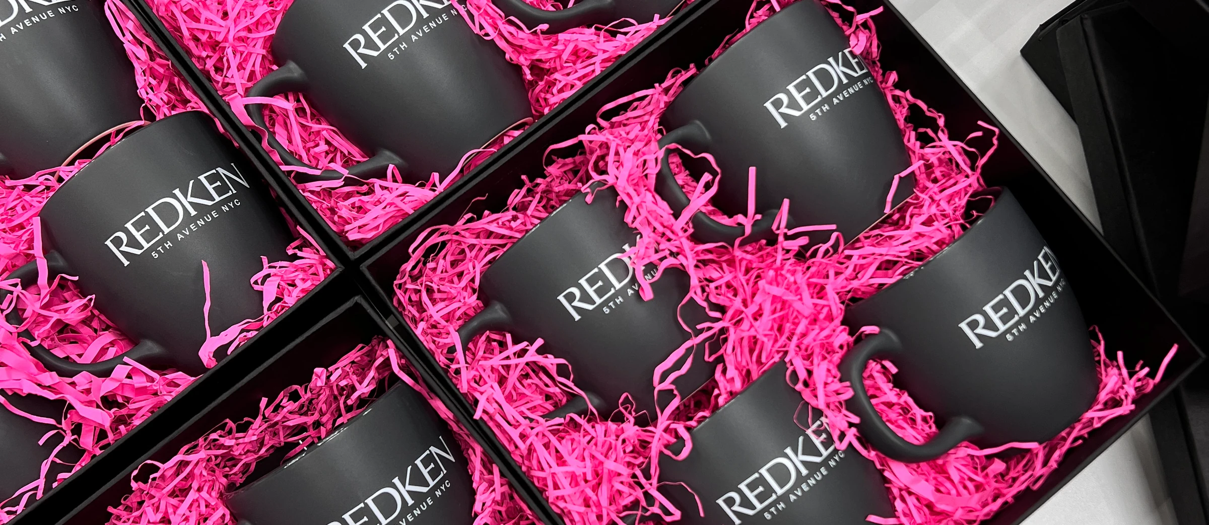 Чорні чашки REDKEN у рожевому наповнювачі у відкритих коробках