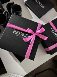 Чорна коробка REDKEN, перев’язана рожевою стрічкою